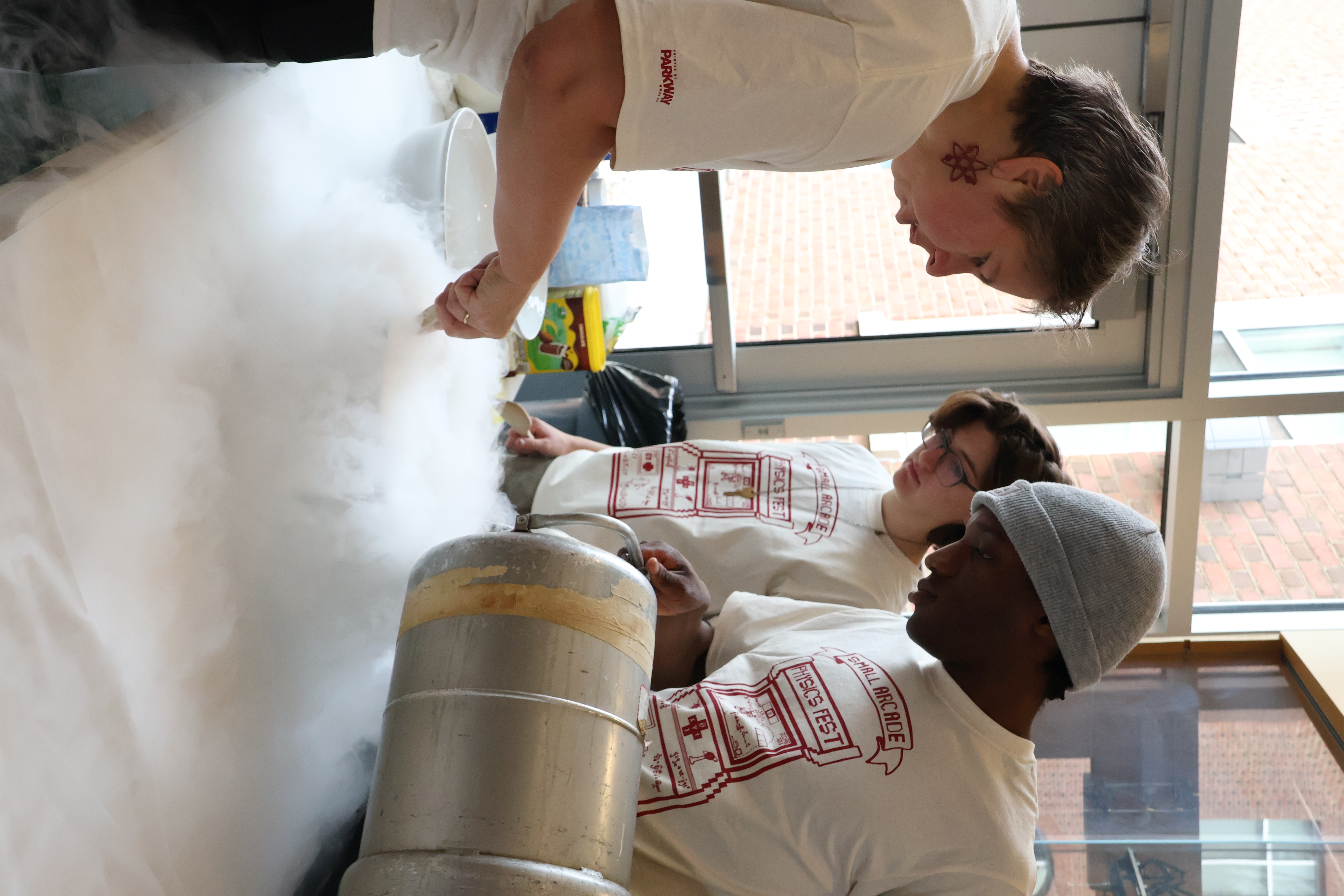 PhysicsFest volunteers pour liquid nitrogen while preparing for an interactive table. Photo by Max Kershner-Hammond